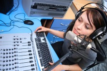 A radio DJ announces news in a studio